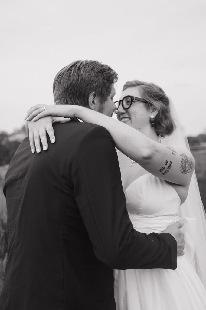 Black and white portrait of a bride and groom smiling at each other.