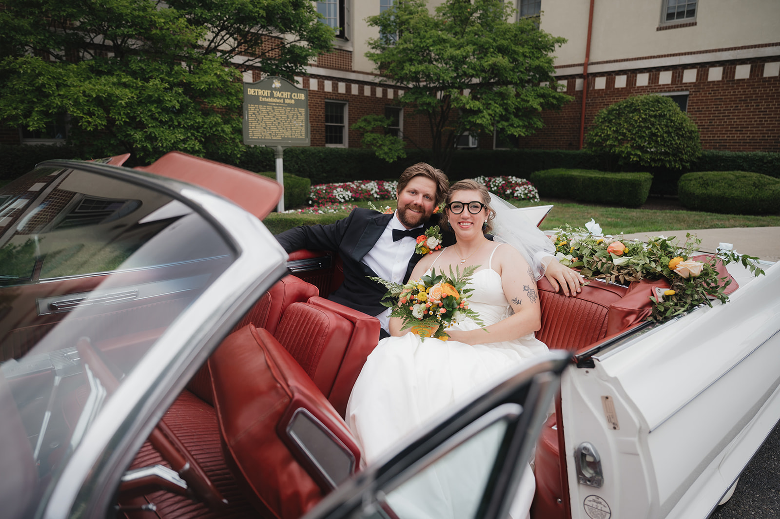 Bride and groom smiling in the back of a vintage Eldorado outside of Detroit Yacht Club.