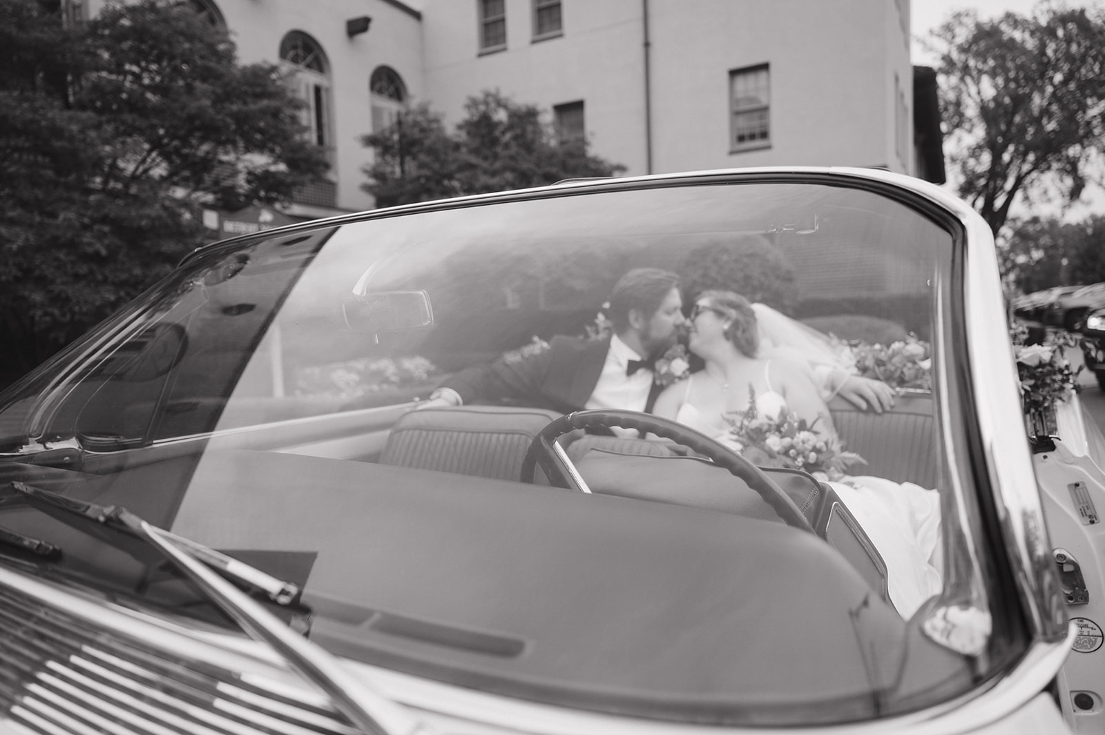 Black and white photo of a bride and groom kissing in the back of a vintage Eldorado outside of Detroit Yacht Club.