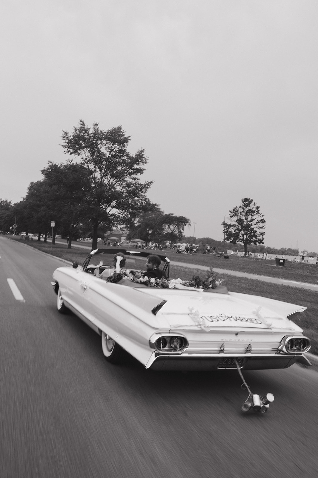 Black and white motion blue photo of a bride and groom driving in Detroit in a vintage Eldorado.