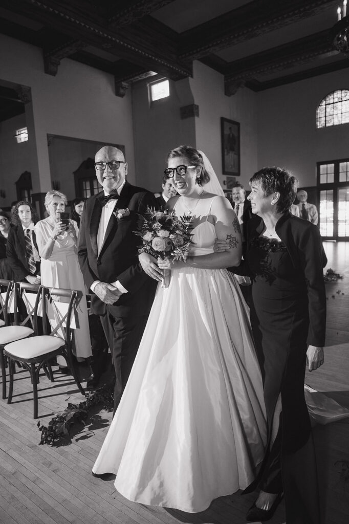 Bride walking down the aisle with her parents at Detroit Yacht Club wedding ceremony.