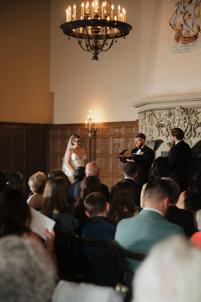 Wedding ceremony taking place inside Detroit Yacht Club with guests seated.
