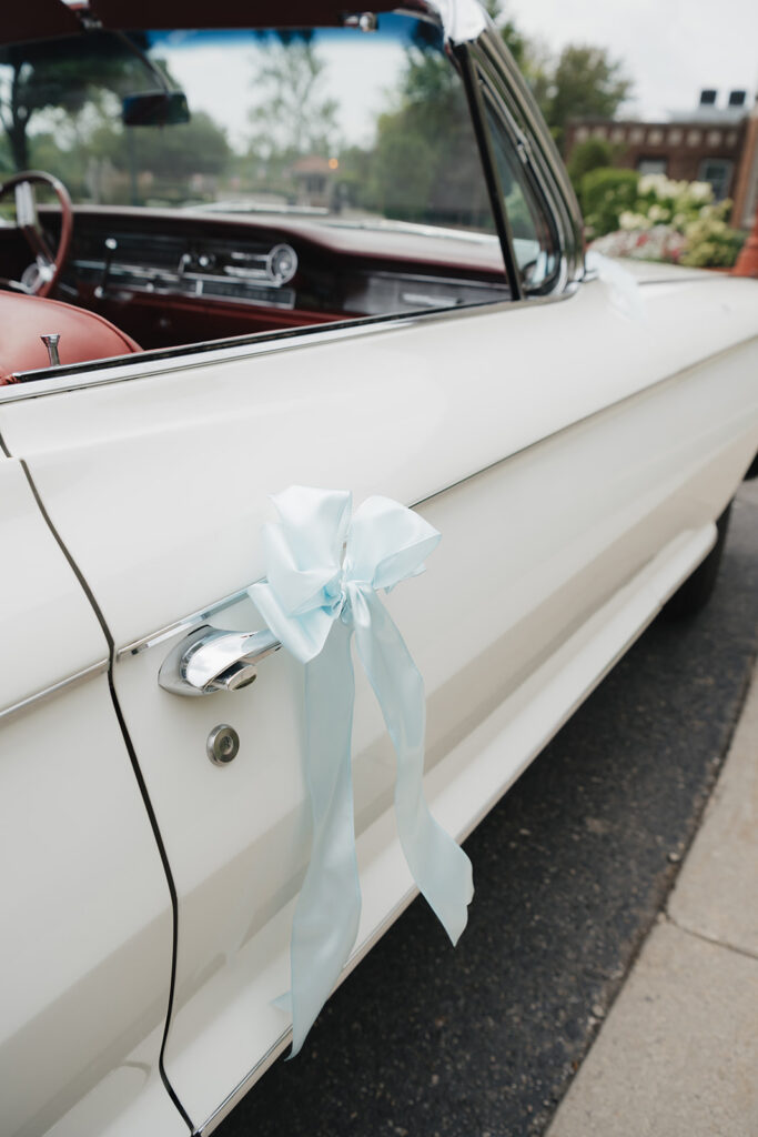 Vintage car with a blue bow tied to the handle.