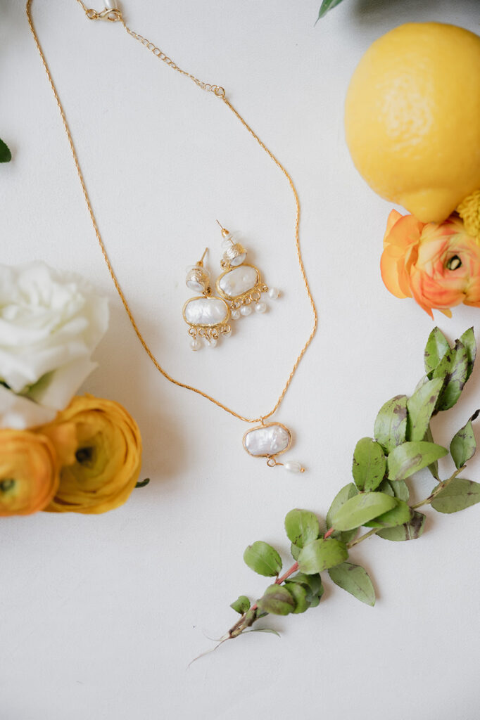 Brides jewelry styled with florals, a lemon, and greenery for a summer Detroit wedding. 