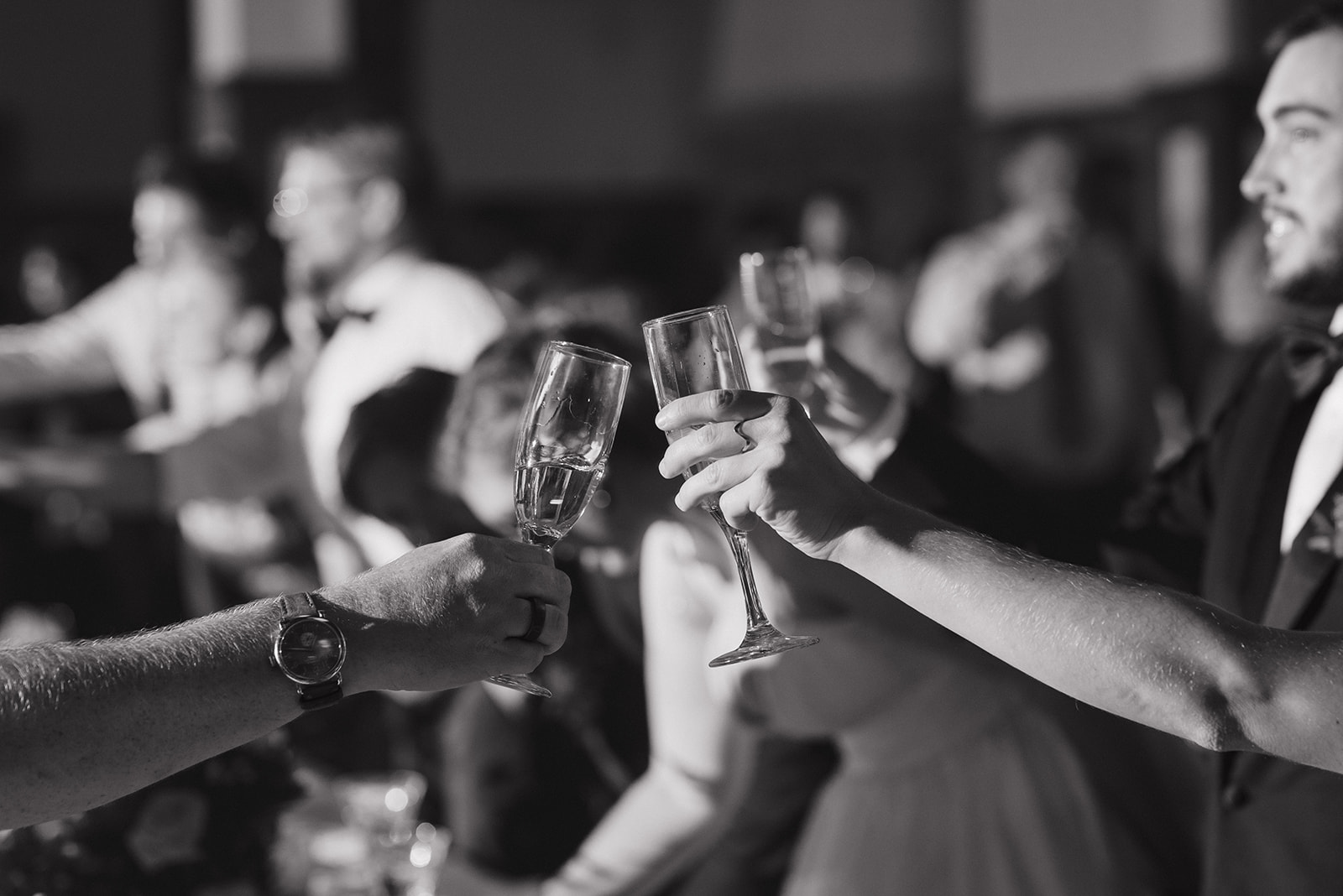 Black and white candid photo of guests toasting during speeches.