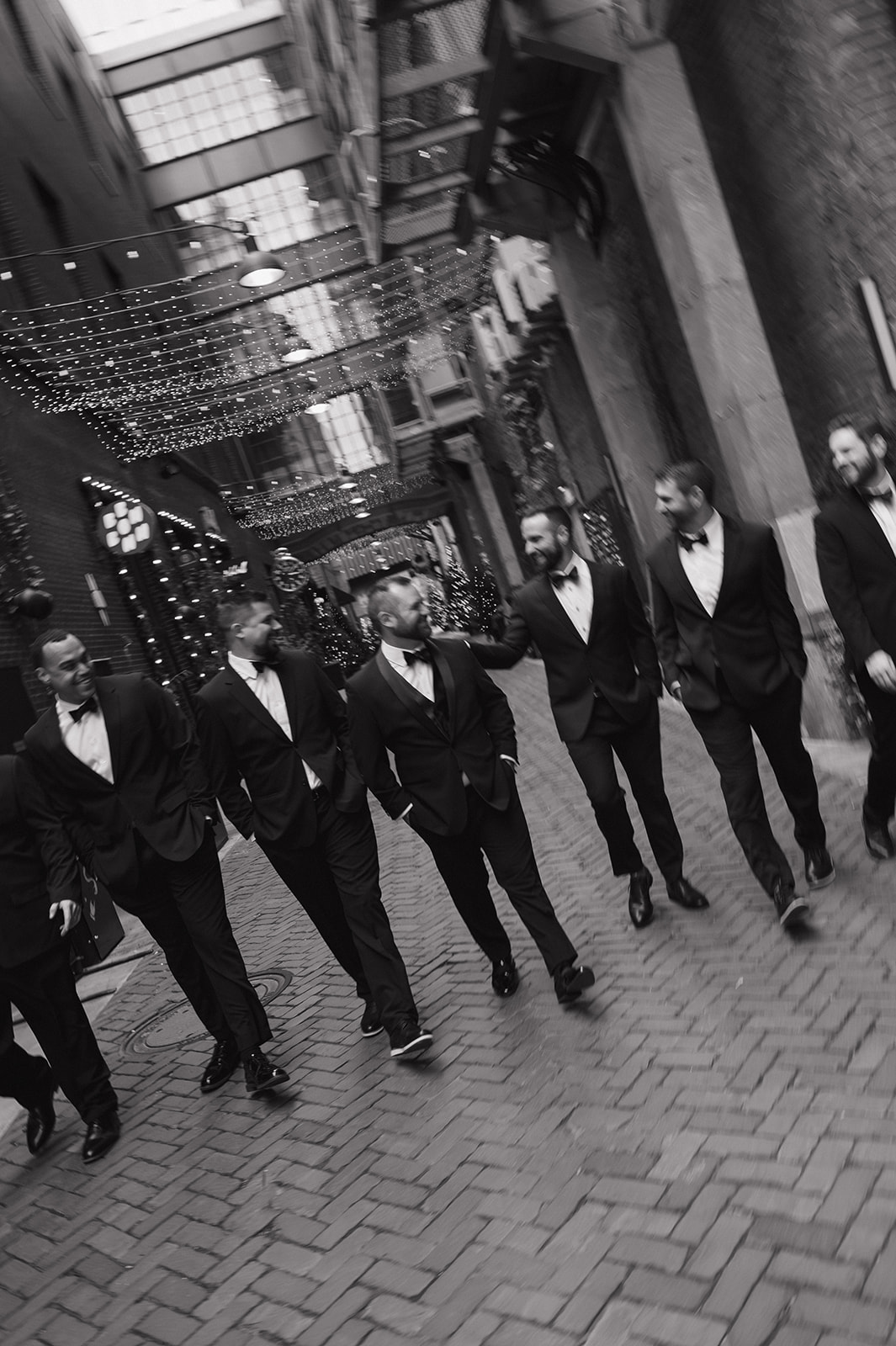 Groom and groomsmen walking together in black and white through downtown Detroit at The Belt alley.