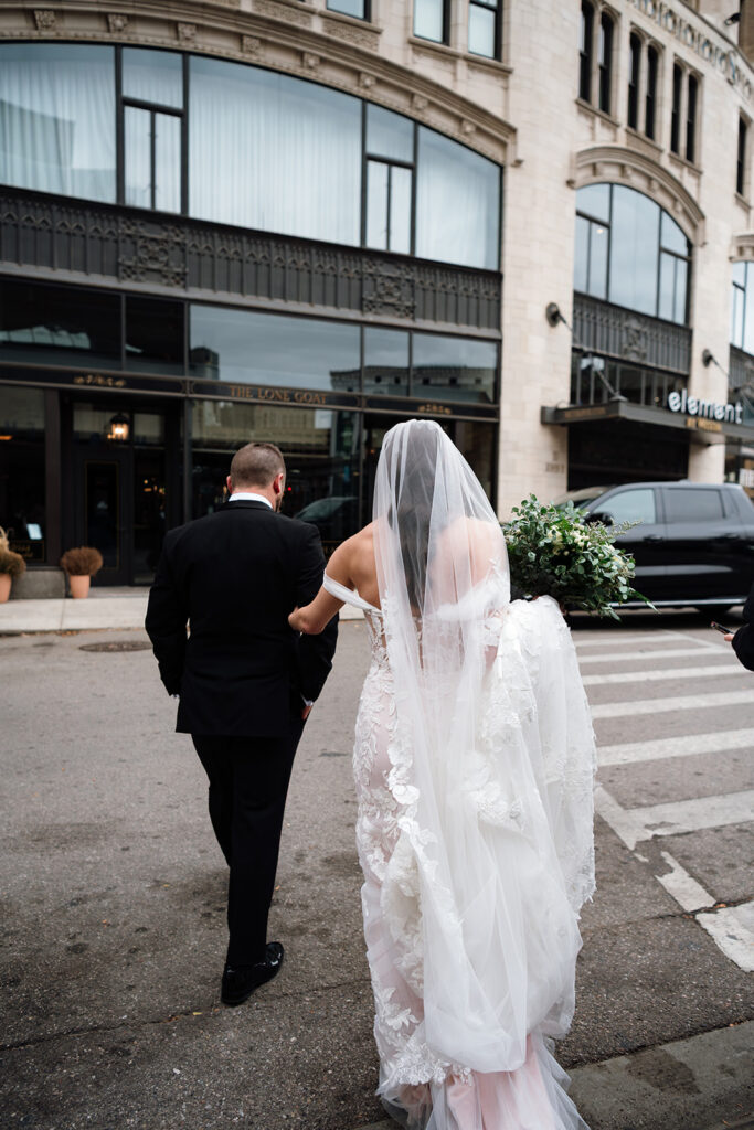 Bride and groom walking across the street in downtown Detroit.