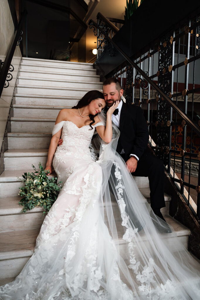 Bride and groom posing on staircase inside Element by Westin Detroit during wedding portraits.
