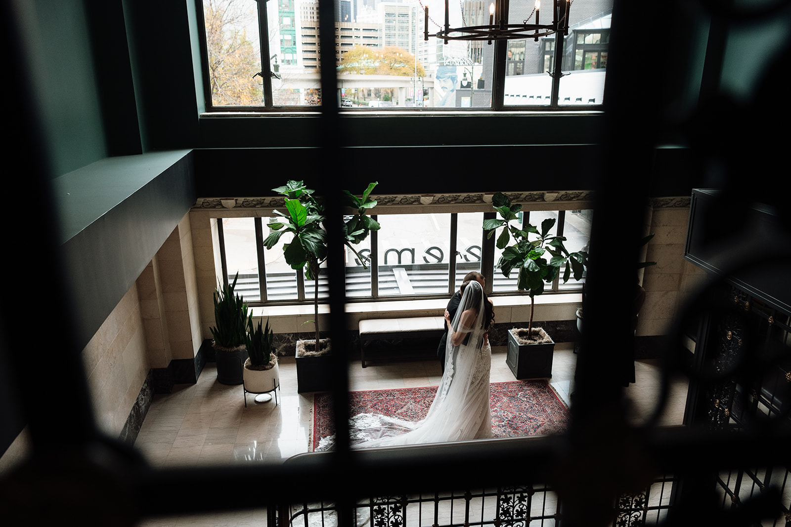 Bride and groom embracing during first look in hotel lobby with large windows at Element by Westin Detroit.