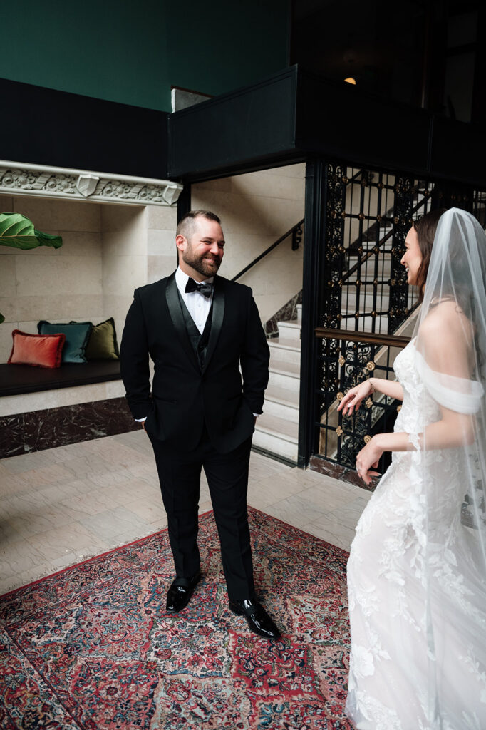 Bride and groom laughing together during first look at Element by Westin Detroit.