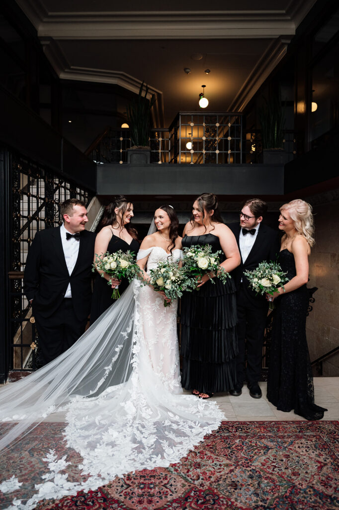 Bride with bridesmaids in black dresses holding bouquets inside Element by Westin Detroit.