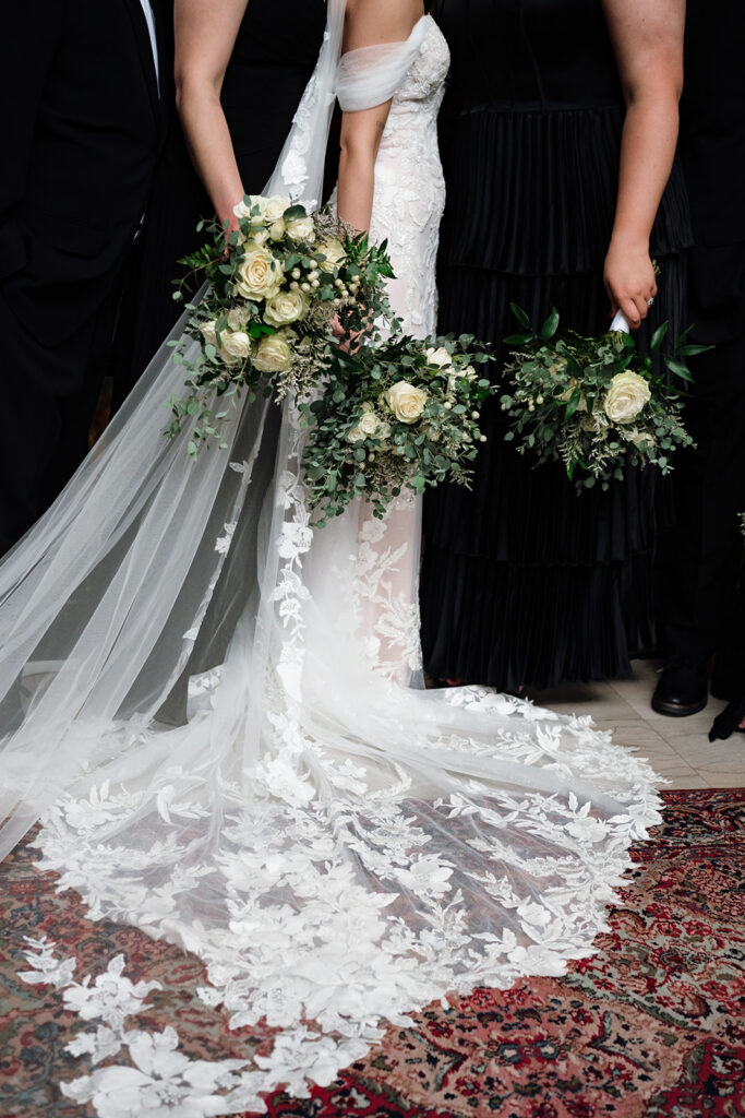 Close up of a bride with bridesmaids in black dresses holding bouquets inside Element by Westin Detroit.