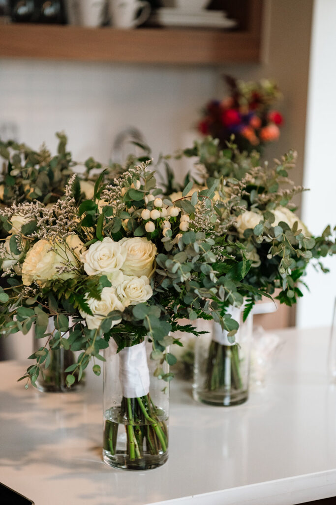 Bridesmaids bouquets resting in vases of water.
