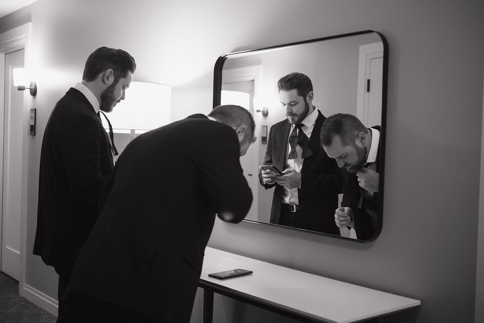 Groom adjusting his tie in the mirror while getting ready at Element by Westin Detroit.
