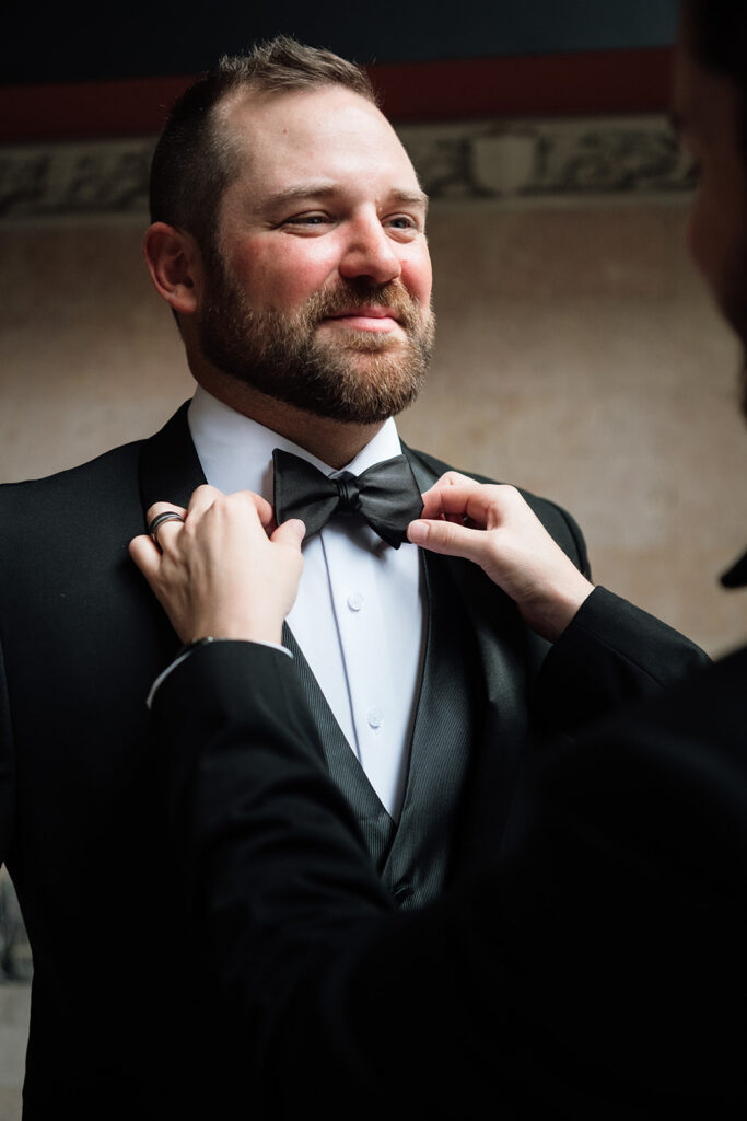 Close up of groom adjusting his bow tie during wedding morning at Element by Westin Detroit.