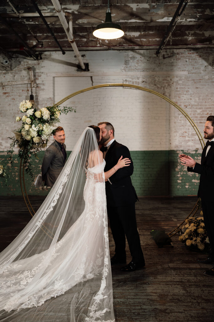 Bride and groom kissing at the altar during Ford Piquette Avenue Plant wedding ceremony.