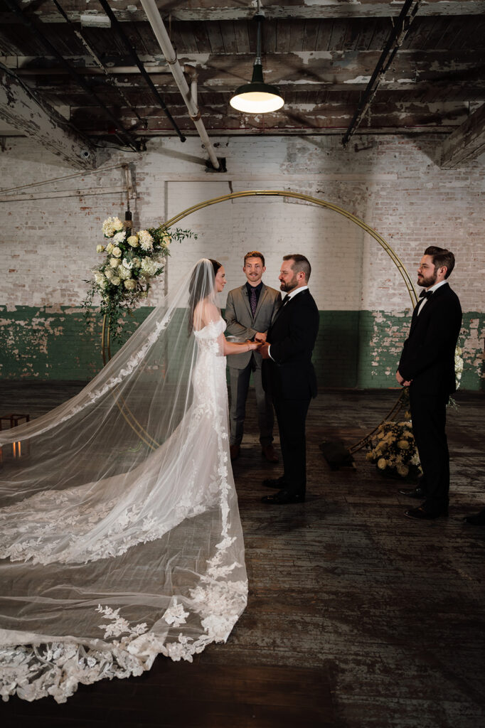 Bride and groom holding hands during ceremony at Ford Piquette Avenue Plant wedding.