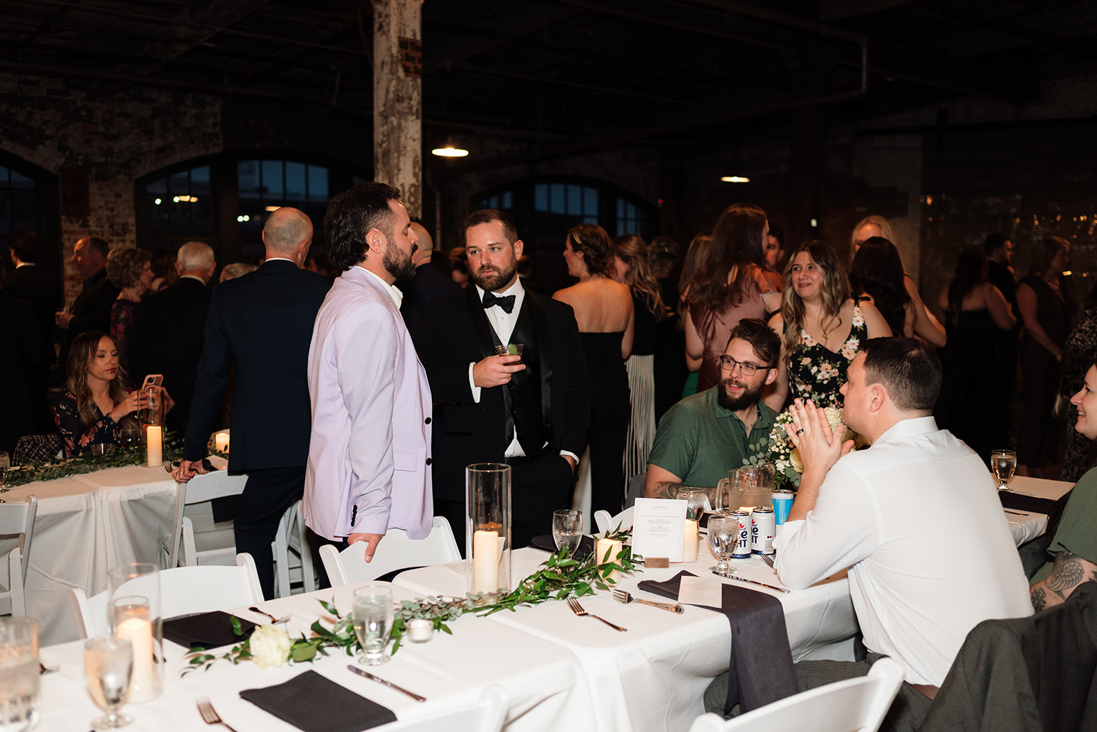 Guests mingling and talking at tables during cocktail hour at Ford Piquette Avenue Plant wedding.