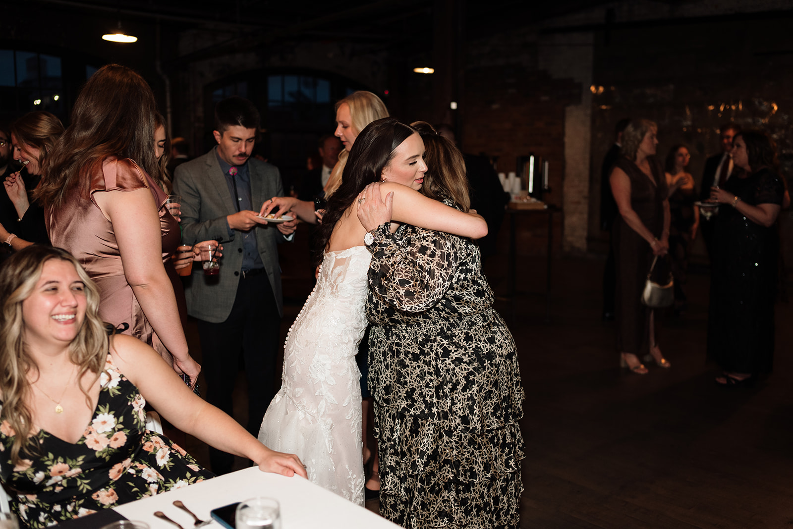 Bride hugging a guest during cocktail hour at Ford Piquette Avenue Plant wedding.