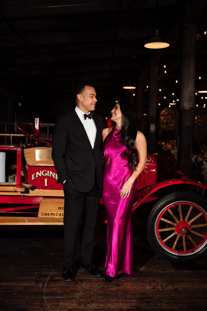 Guest couple smiling for portrait in front of vintage car at Ford Piquette Avenue Plant.