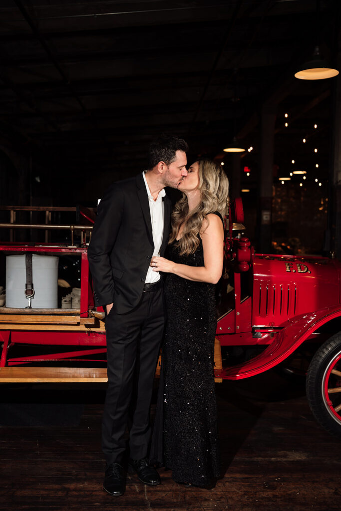 Guest couple smiling for portrait in front of vintage car at Ford Piquette Avenue Plant.
