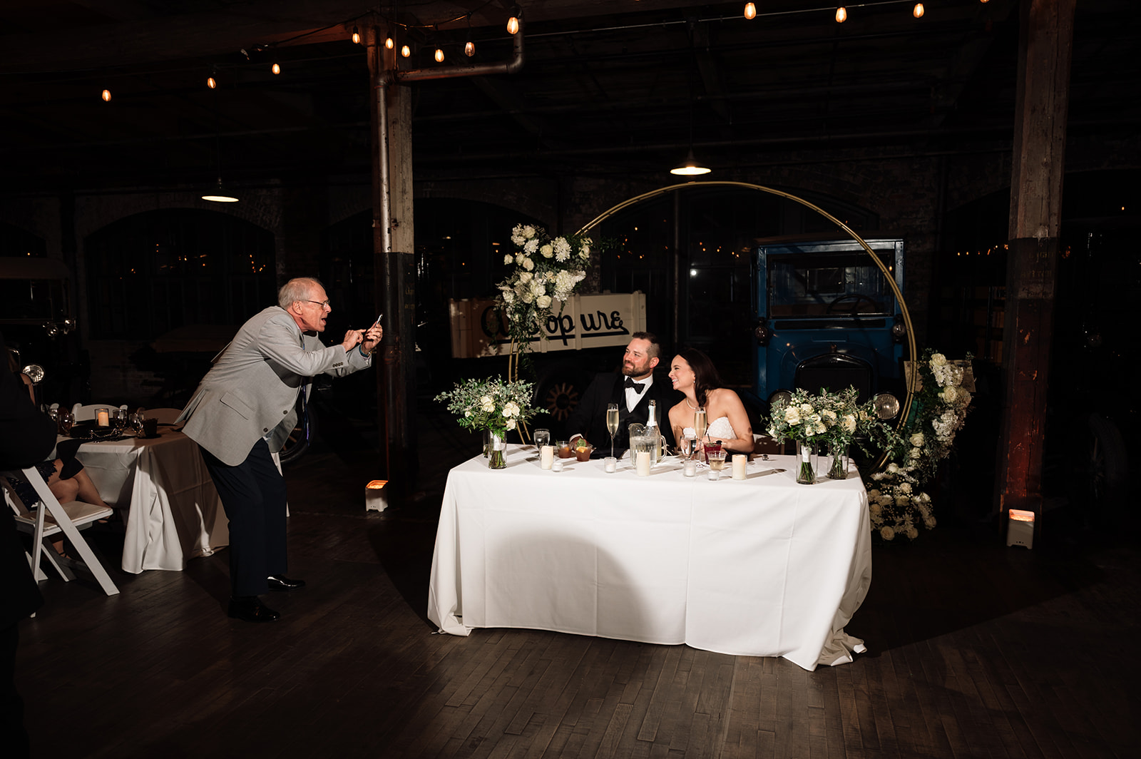Guest taking a phone photo of the bride and groom at their sweetheart table. 