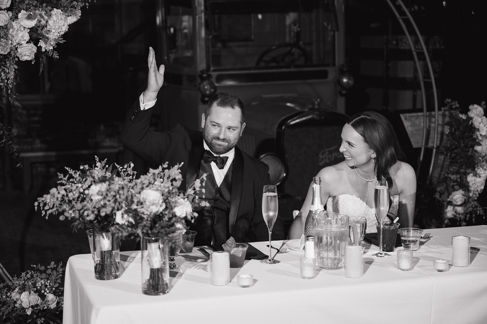 Black and white photo of a bride and groom laughing during speeches.