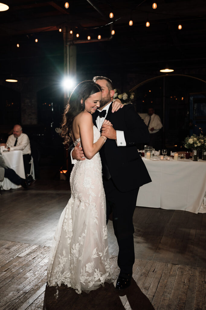 Bride and groom sharing first dance under string lights at Ford Piquette Avenue Plant reception.