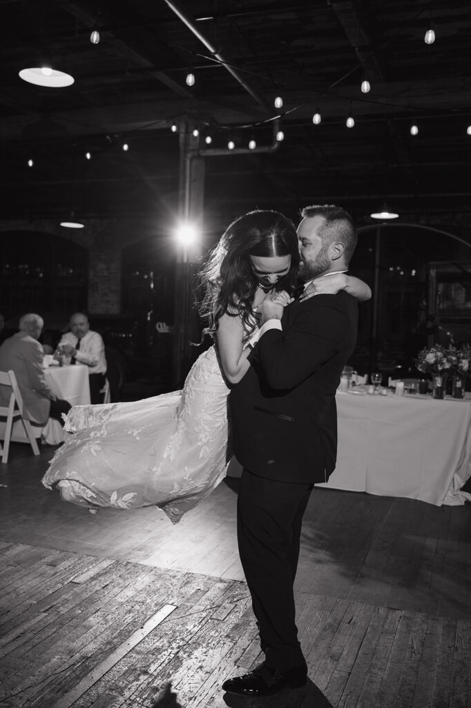 Bride and groom sharing first dance under string lights at Ford Piquette Avenue Plant reception.