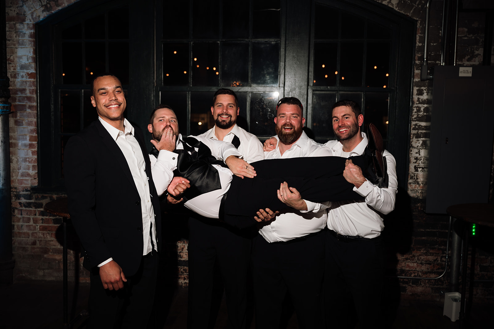 Groomsmen holding up the groom for a funny reception portrait.