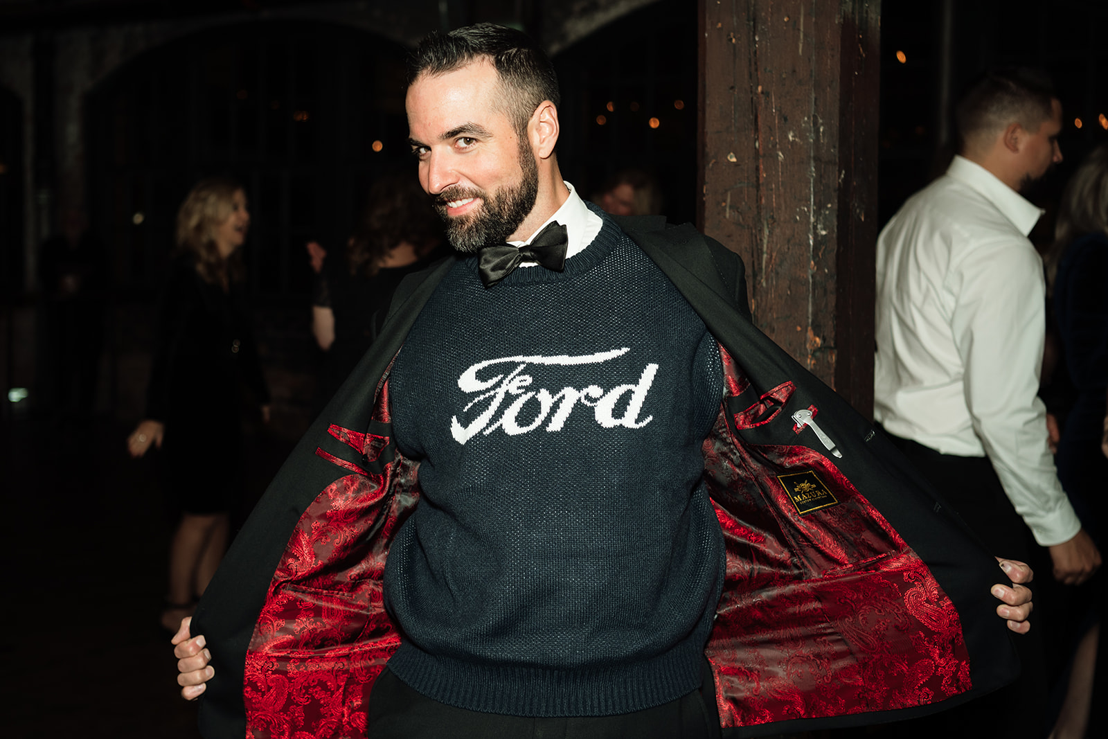 Guest opening his suit and showing his Ford sweater underneath. 