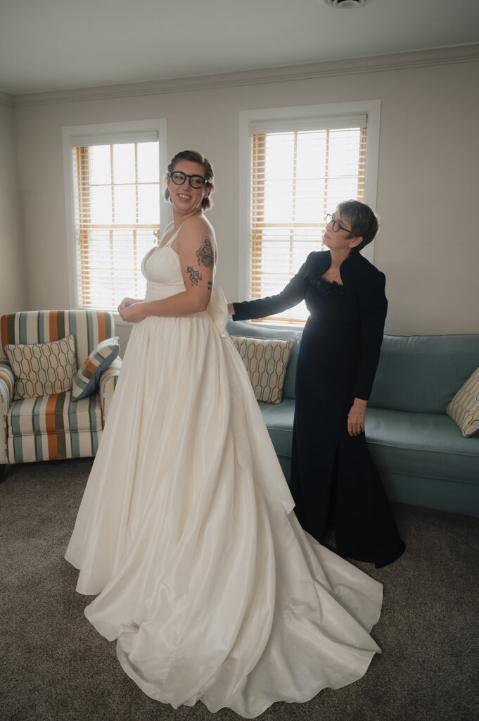 Brides mother helping her get into her wedding dress.