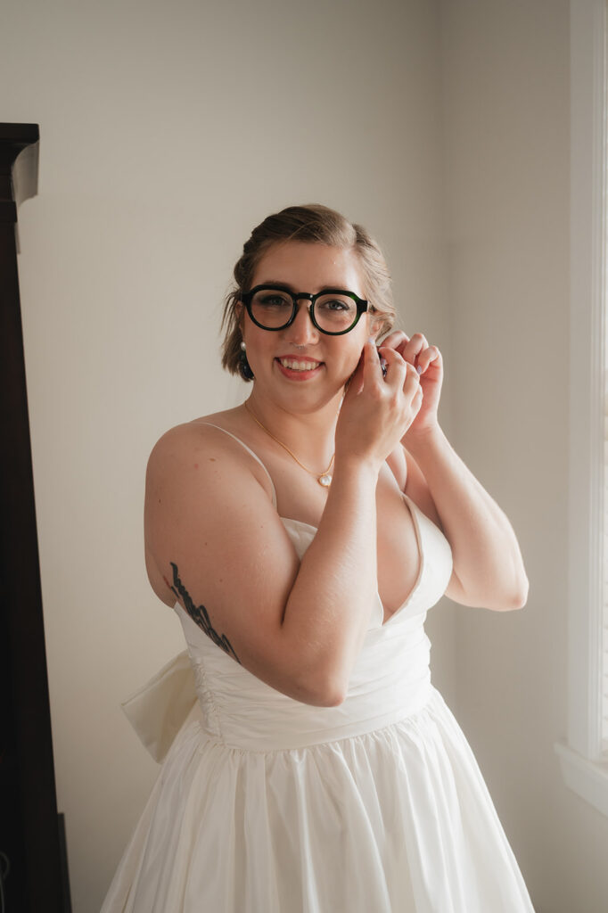 Bride adjusting her earrings as she gets ready for her wedding day.