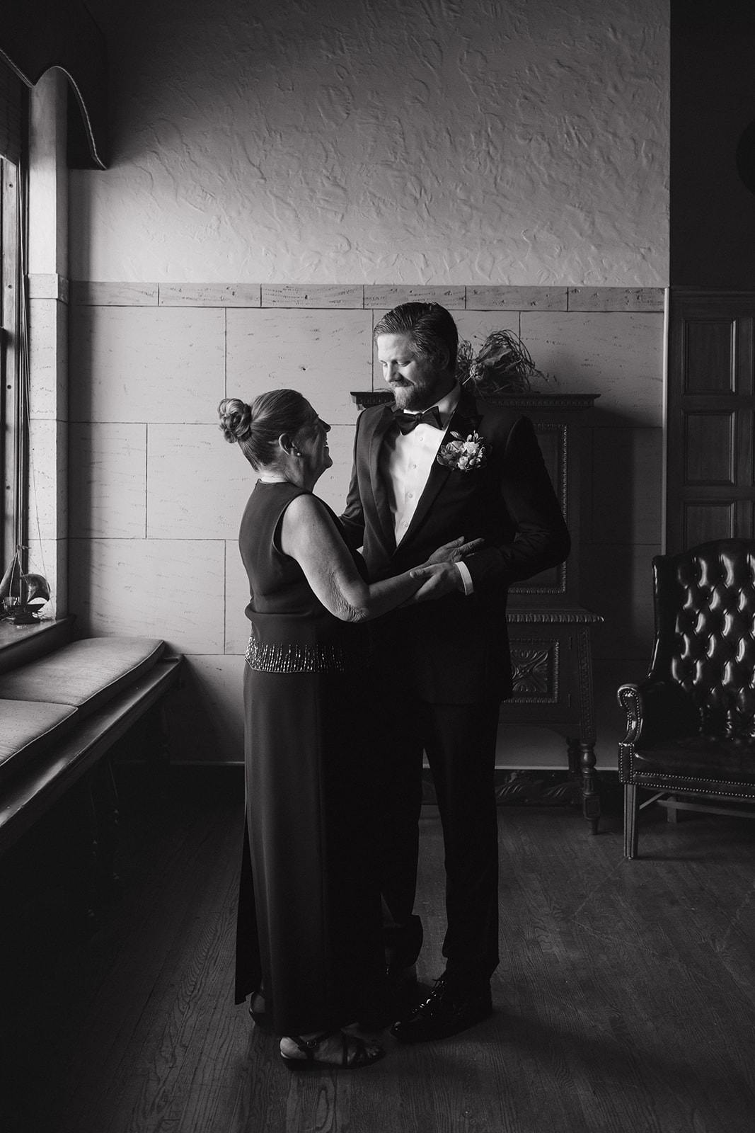 Black and white photo of the groom and his mother sharing a moment.