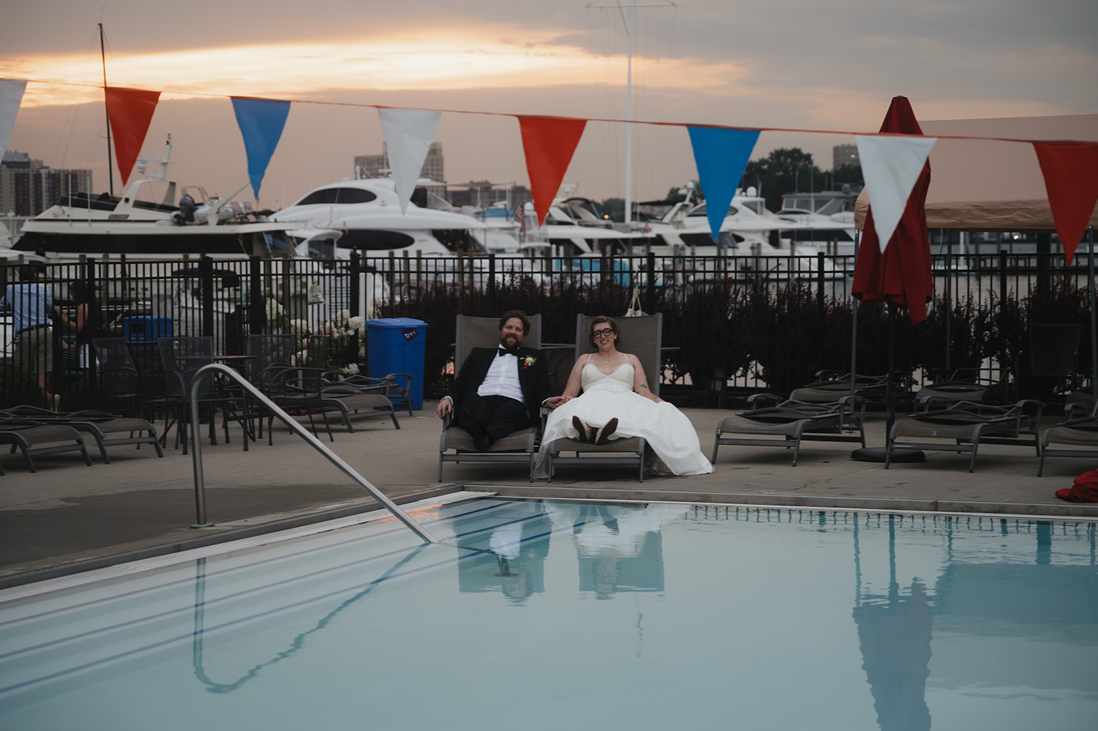 Bride and groom lounging in chairs by the DYC pool for their portraits.