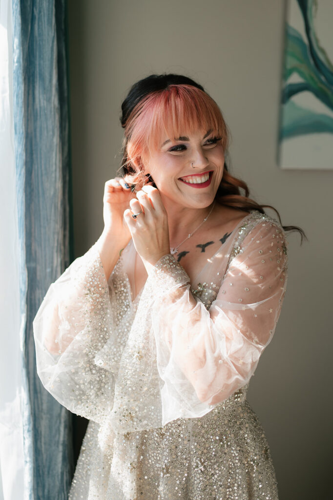 Bride smiling while putting her earrings in.