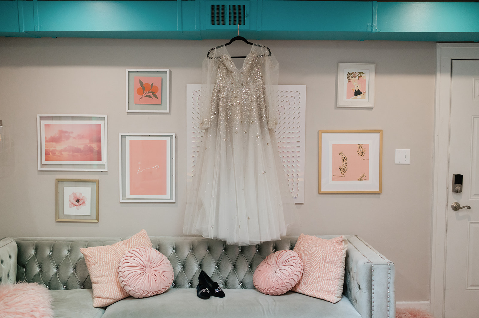Wedding dress hanging above a pastel couch for a Ferndale Michigan wedding.