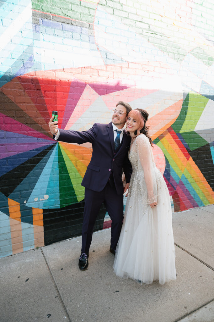 Bride and groom taking a selfie in front of a colorful mural during their Ferndale Michigan wedding.