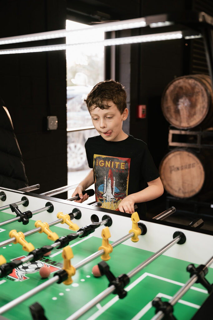 Child playing foosball during a relaxed rehearsal dinner at Dog and Pony Show Brewing.
