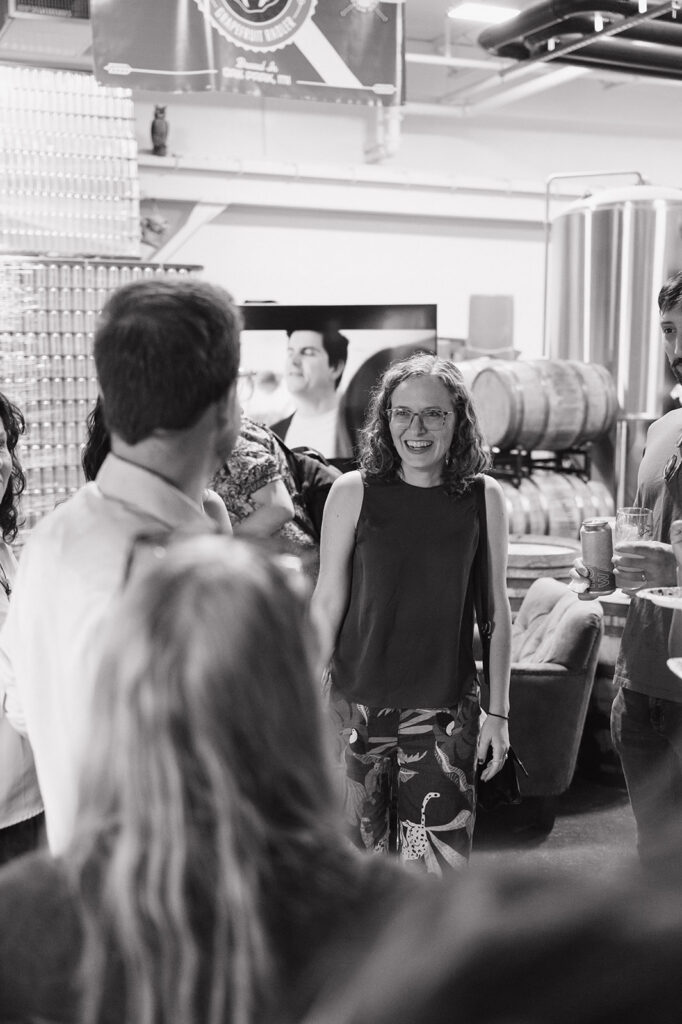 Guests mingling at Dog and Pony Show Brewing during a black and white rehearsal dinner photo.