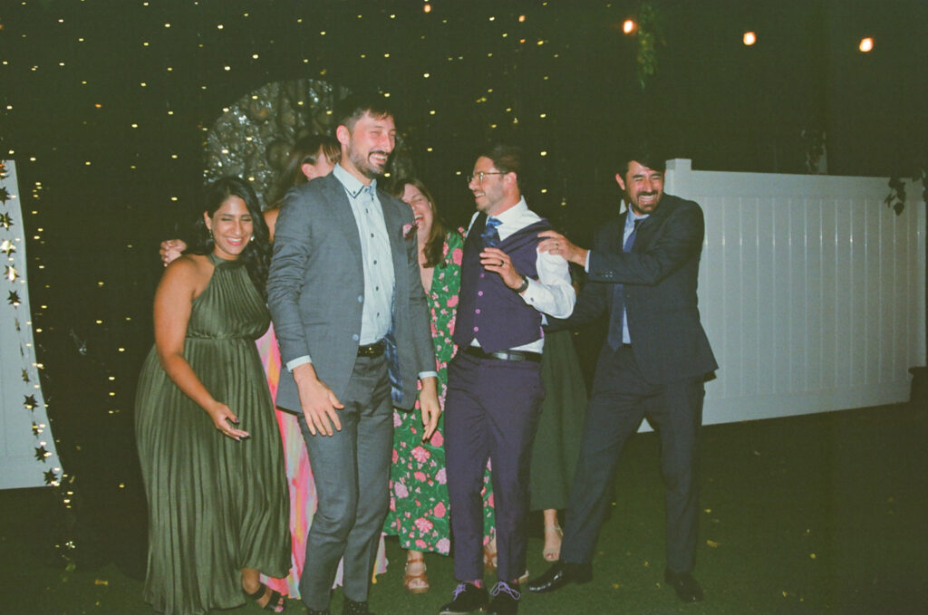Groom laughing with wedding guests during a Detroit Fleat wedding reception on film.