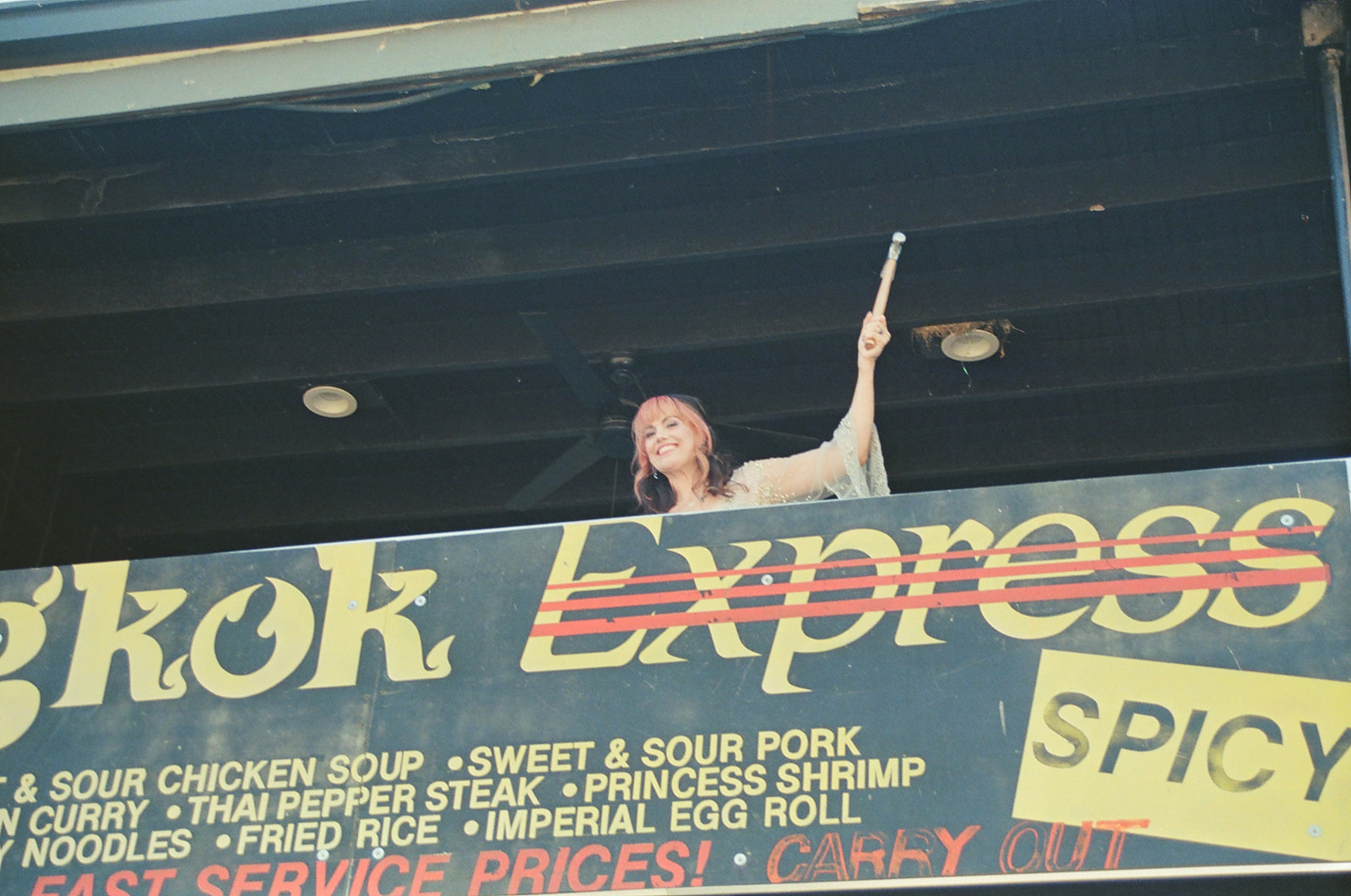 Bride standing above a vintage sign during her Ferndale Michigan wedding on film.