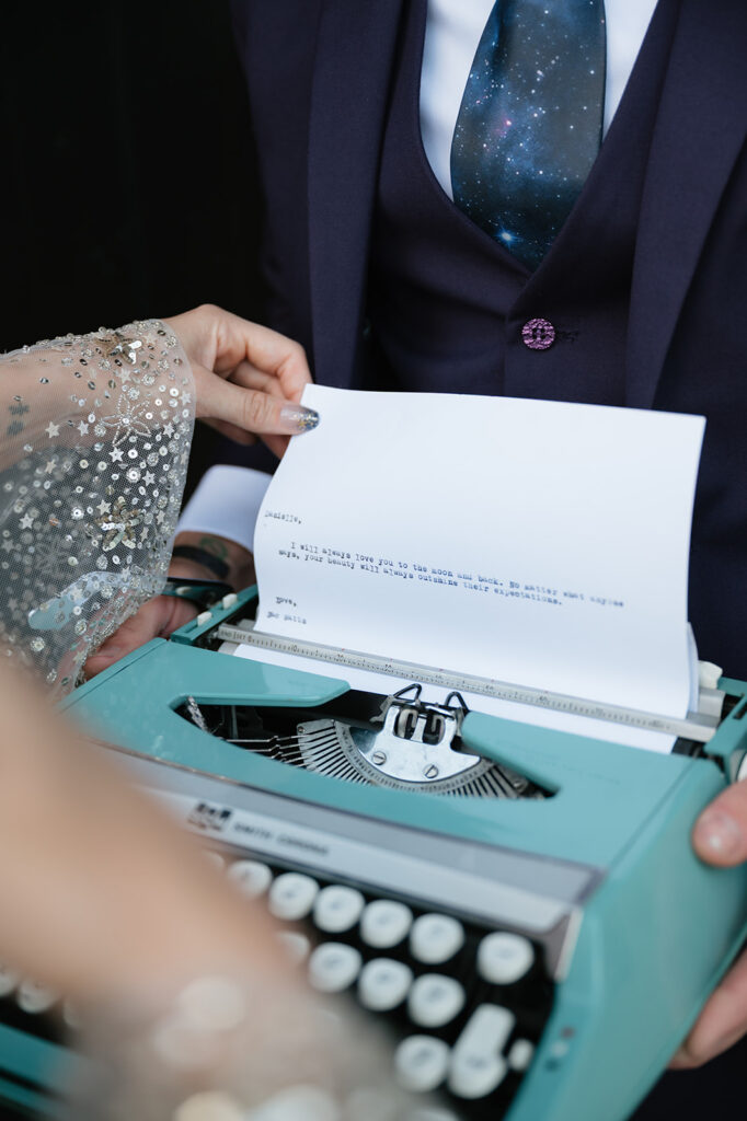 Close-up of a typed wedding letter held over a vintage typewriter during a Ferndale Michigan wedding.