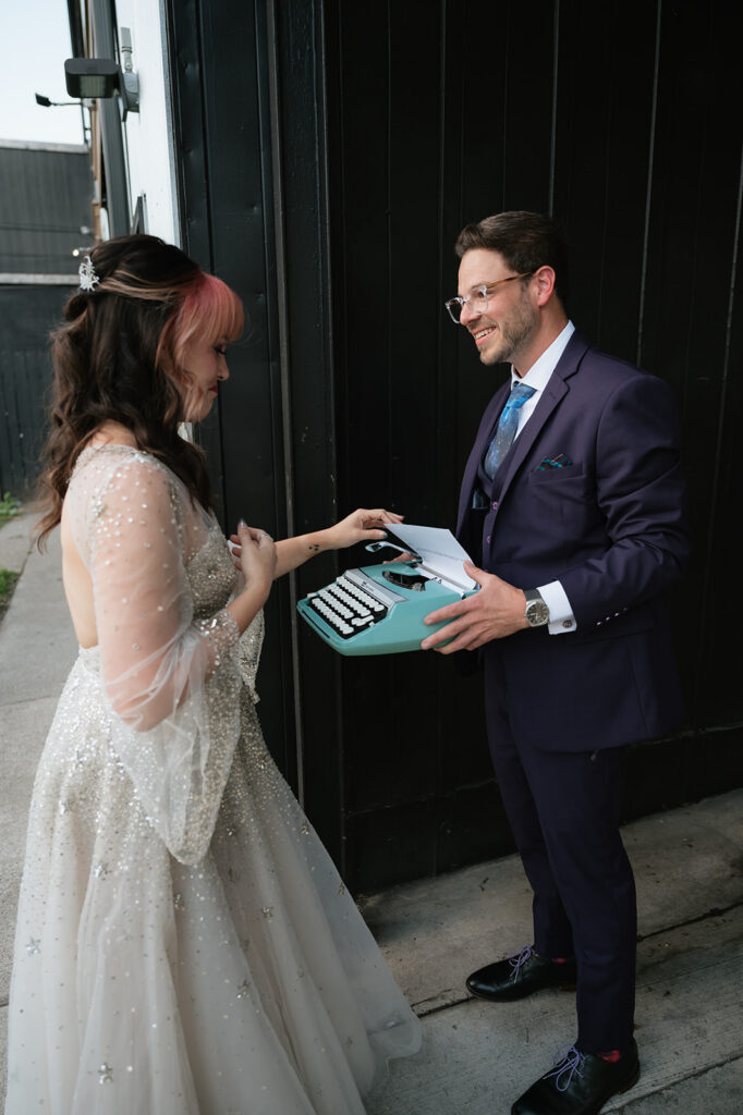 Groom smiling while holding a vintage typewriter gift during his Ferndale Michigan wedding.