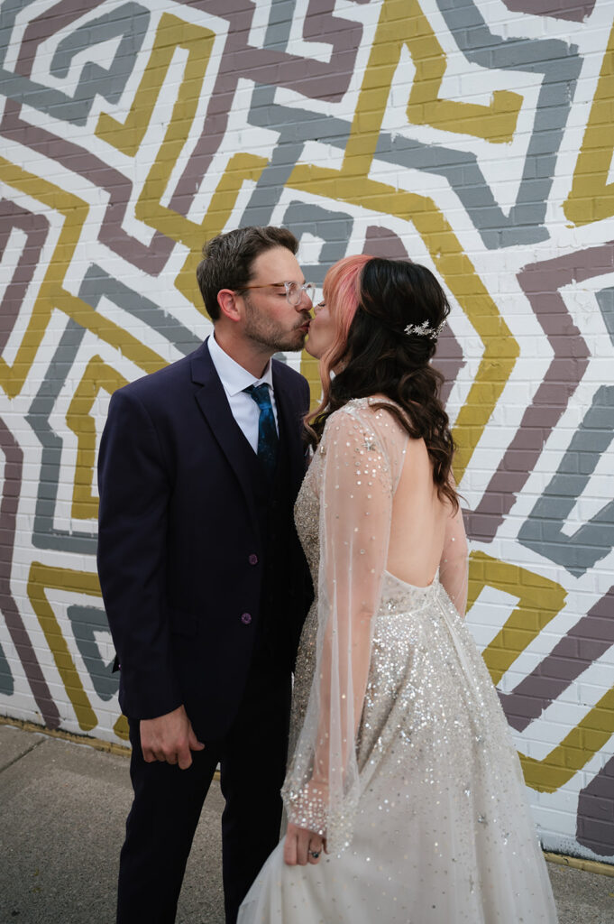 Bride and groom kissing in front of a colorful mural during their Ferndale Michigan wedding.