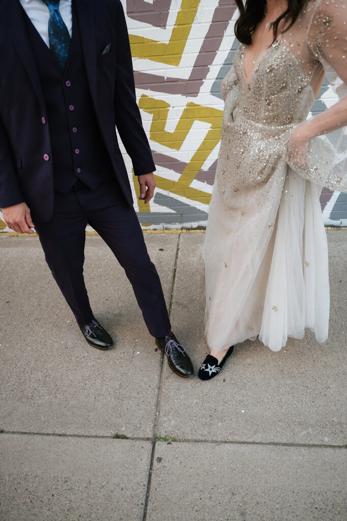 Bride and groom showing off their space-themed wedding shoes.