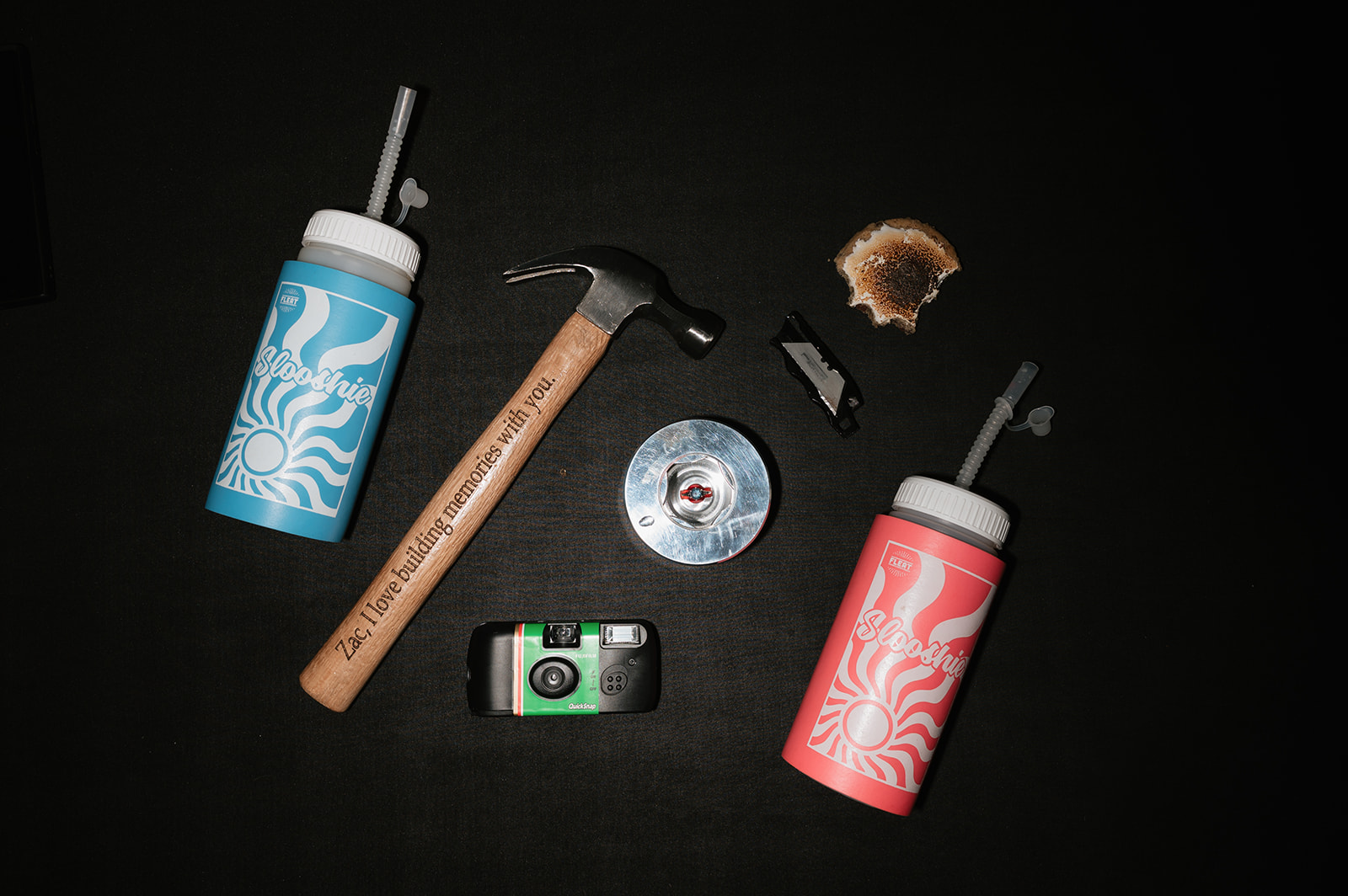 Fun wedding detail shot with hammer, Slooshie cups, a cookie, and disposable camera.