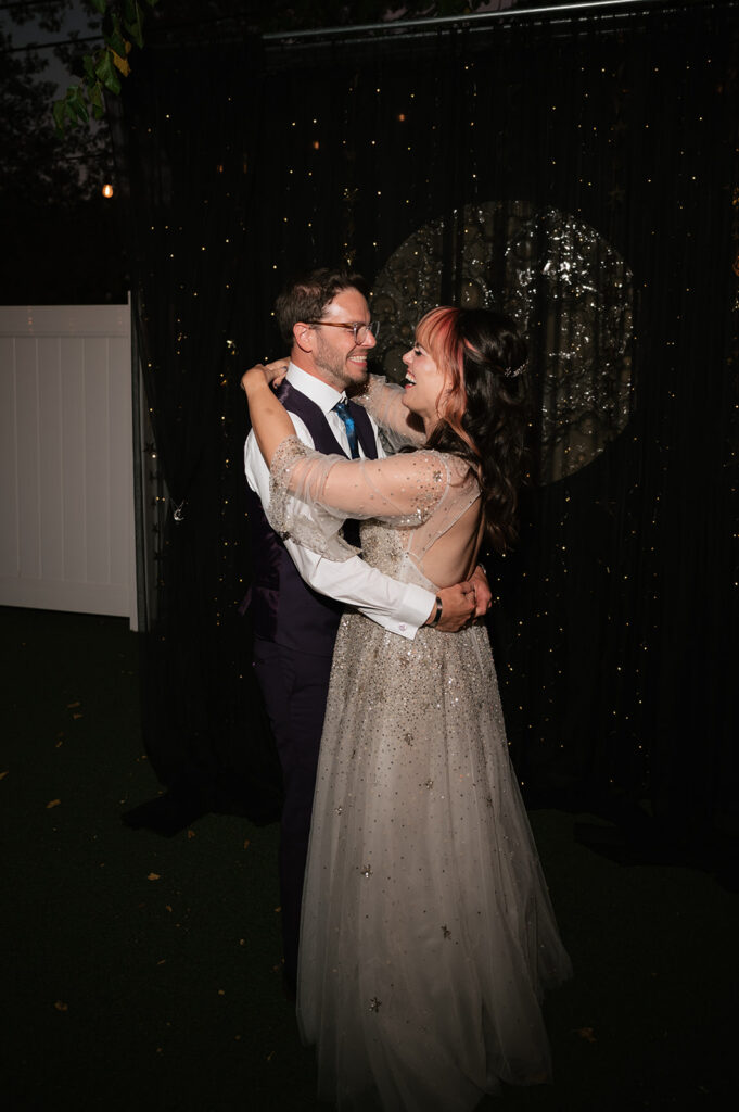 Bride and groom dancing in front of their custom make moon backdrop.