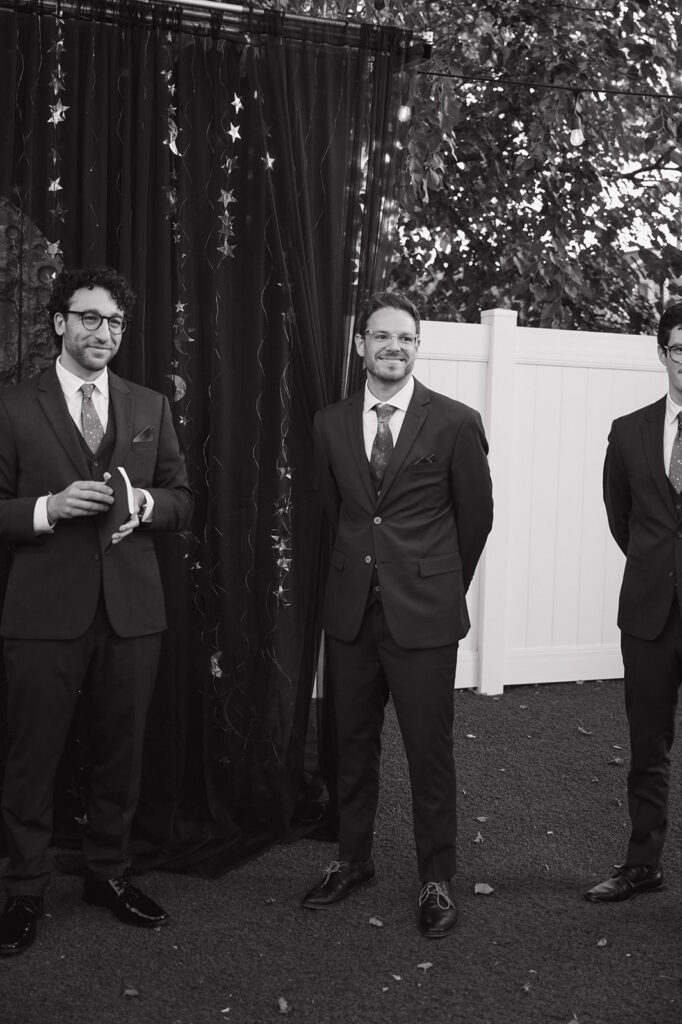 Groom standing with groomsmen in front of a handmade moon backdrop at Detroit Fleat.