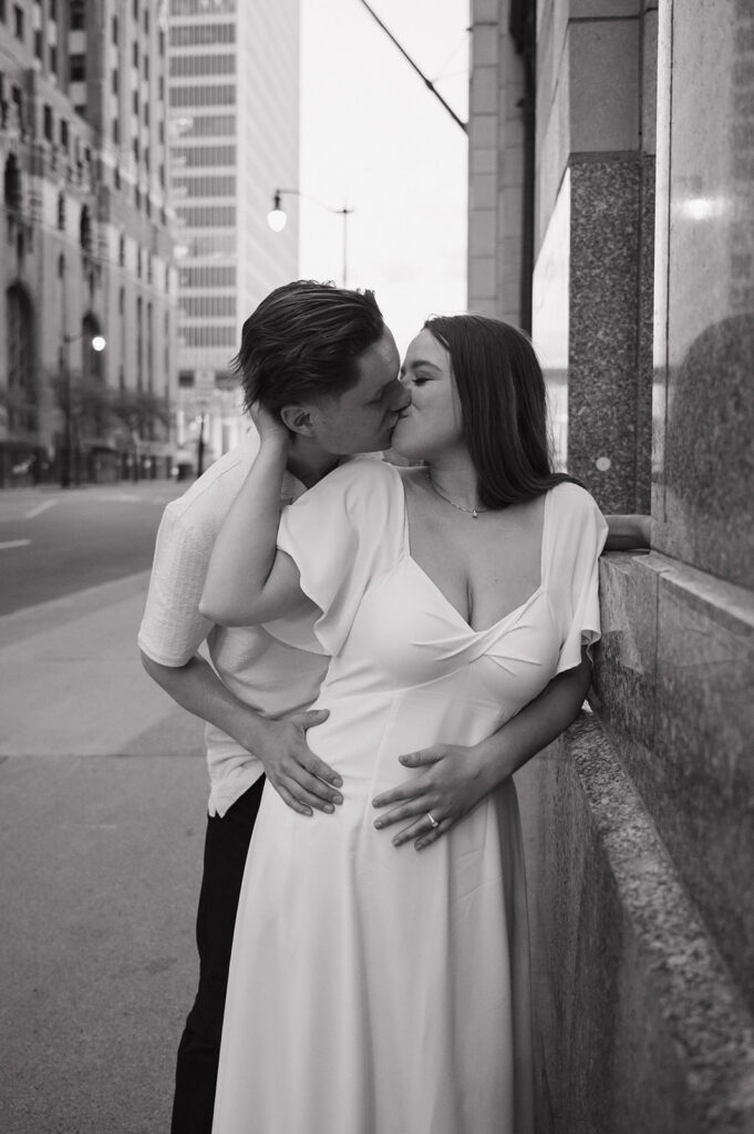 Couple holding hands under warm lights during their downtown Detroit engagement photos.